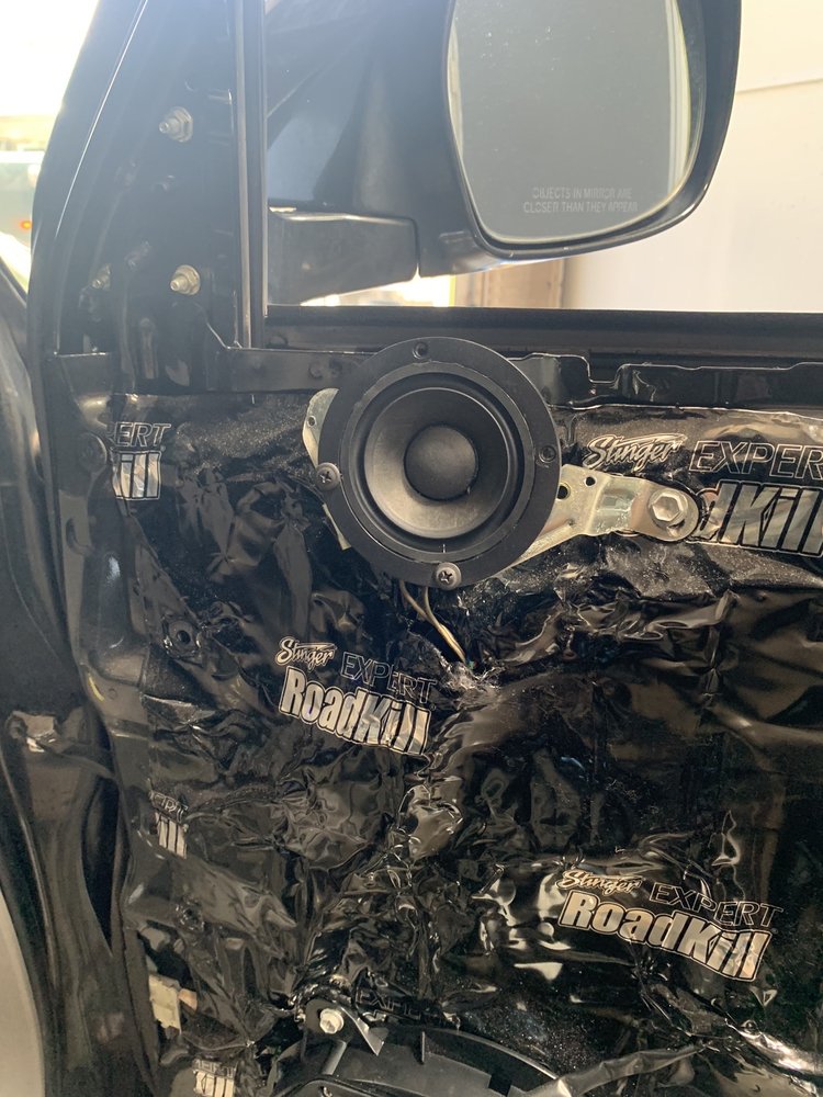 A car featuring a speaker embedded in the door, wrapped in sleek black plastic, displayed at the Puresounds store.