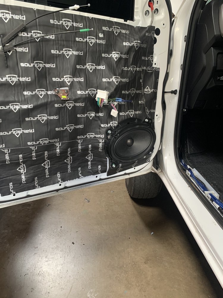 A white car door featuring a speaker and speaker box, showcasing the Puresounds store stereo system.